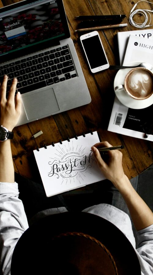 how can I start an online business | Freedom For You 2 Top view of a creative workspace with laptop, coffee, and hand lettering for design inspiration.